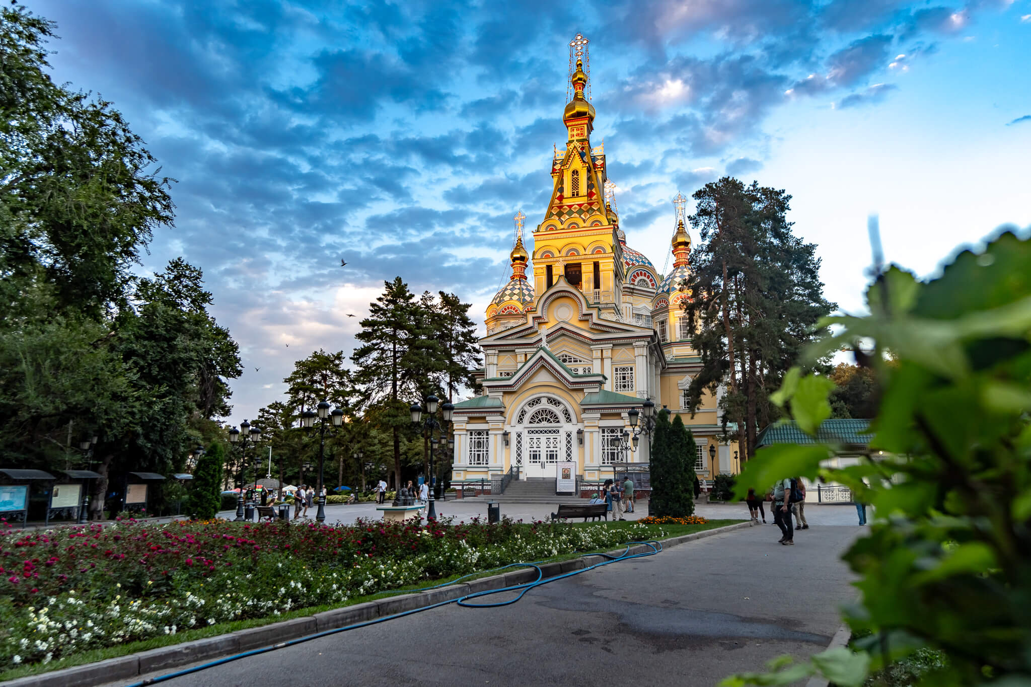 Christi-Himmelfahrt-Kathedrale im Panfilov-Park in Almaty Christi-Himmelfahrt-Kathedrale mit goldenen Kuppeln im Panfilov-Park in Almaty, davor Blumenbeete und Spaziergänger