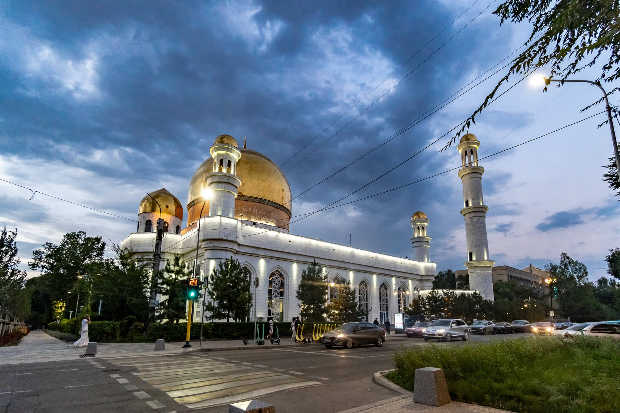 Almaty Sehenswürdigkeiten: Die schönsten Highlights & meine 8 Tipps 1 Weiße Moschee mit goldenen Kuppeln und Minaretten unter bewölktem Abendhimmel in Almaty, davor eine Straße mit Autos